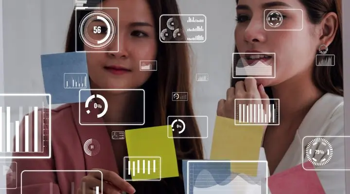 Dos mujeres miran notas adhesivas sobre vidrio, superpuestas con datos digitales e íconos gráficos, que sugieren análisis o planificación, posiblemente descubriendo información de los canales invisibles del tráfico social o de Dark social.