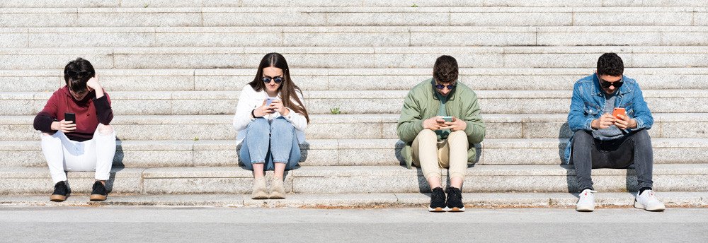 Conjunto de personas sentadas con un móvil siendo una generación incomunicada