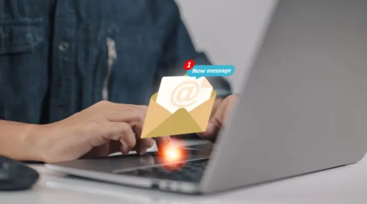 Una persona escribiendo en una computadora portátil mientras aparece un gráfico digital de una notificación de correo electrónico sobre el teclado, resaltando el valor de un suscriptor con cada nuevo mensaje recibido.