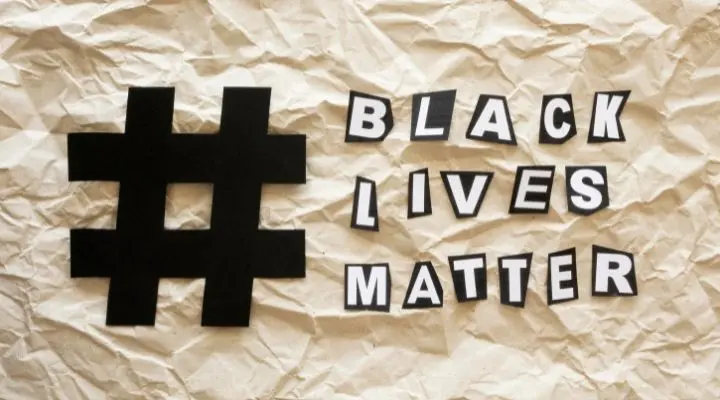 Un gran símbolo de hashtag negro y las palabras "Black Lives Matter" escritas en letras recortadas sobre un fondo de papel arrugado evocan el poder de los hashtag Los en el activismo moderno.