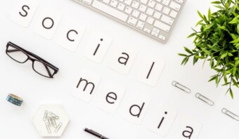 Un teclado, gafas, una planta y clips se disponen alrededor de las palabras "mentiras del social media" escritas en tarjetas.