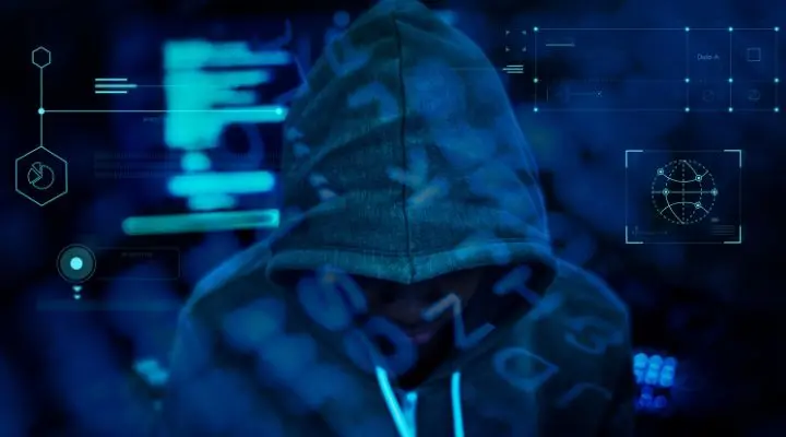Persona con una sudadera con capucha rodeada de gráficos y códigos digitales, evocando la atmósfera misteriosa de la Deep Web en un entorno oscuro de temática tecnológica.