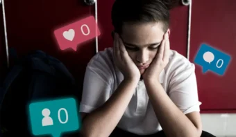 Un joven se sienta con la cabeza entre las manos, rodeado de íconos de notificaciones de redes sociales que muestran cero “me gusta”, mensajes y seguidores: una imagen poderosa que refleja el impacto del marketing emocional en la autoestima.