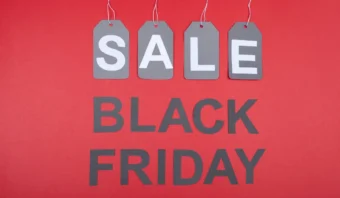 Las etiquetas de oferta de color gris cuelgan sobre un texto en negrita que dice "Viernes Negro" sobre un fondo rojo, capturando la emoción de las ofertas de El Buen Fin.