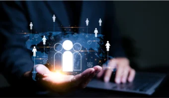 Una persona con traje sostiene en la palma de su mano un icono brillante de personas, que simboliza futuros clientes, con una computadora portátil y una red digital de figuras humanas y un mapa del mundo iluminando el fondo.