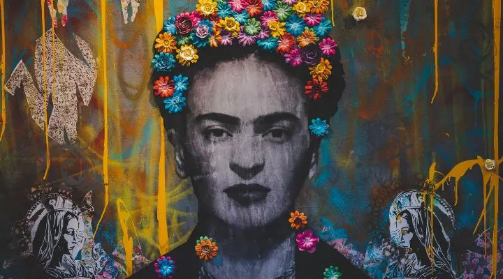 Un mural colorido personifica la Creatividad Mexicana, mostrando a una mujer adornada con flores en el cabello sobre un fondo vibrante y abstracto.