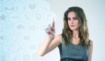Una mujer interactúa con una interfaz de pantalla táctil virtual, haciendo clics rápidos en íconos de tecnología y aplicaciones sobre un fondo claro.