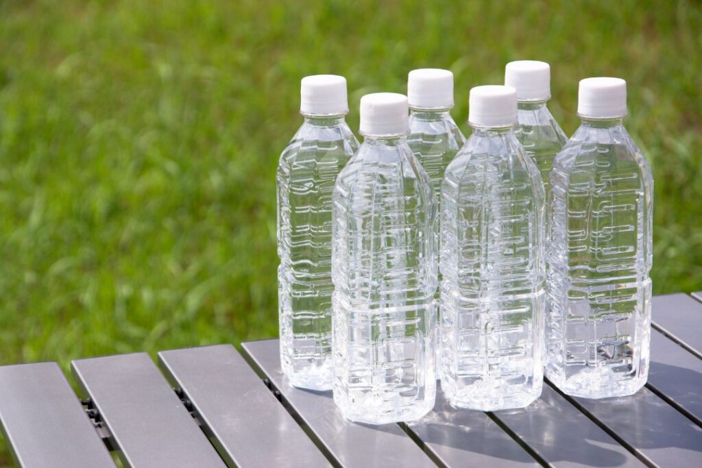 Seis botellas de agua sobre una mesa en el césped.