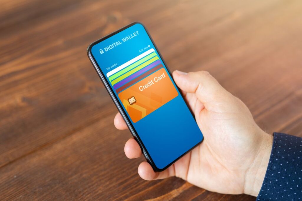 Un consumidor digital sosteniendo un teléfono inteligente con una tarjeta de crédito.