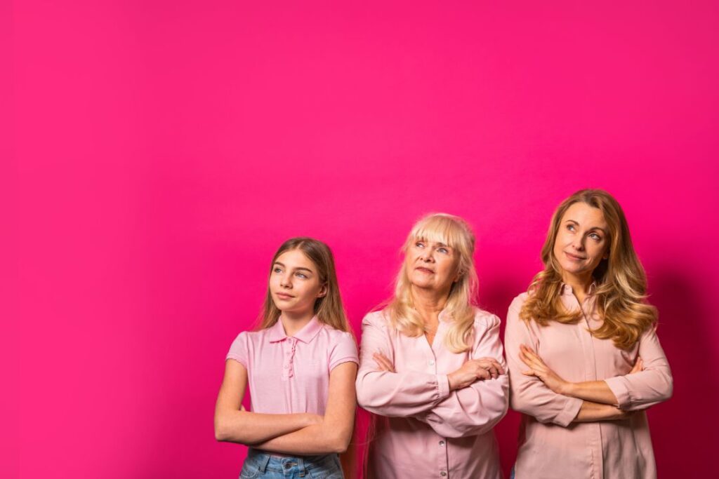 Tres mujeres con diferentes hábitos abrazando nuevos hábitos frente a una pared rosa.