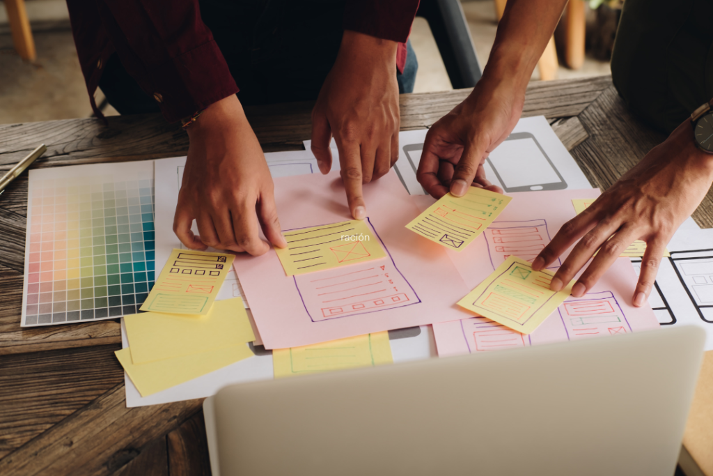 Sobre mesa puesta con personas agarrando Post-it planeando algo como Estrategia de venta