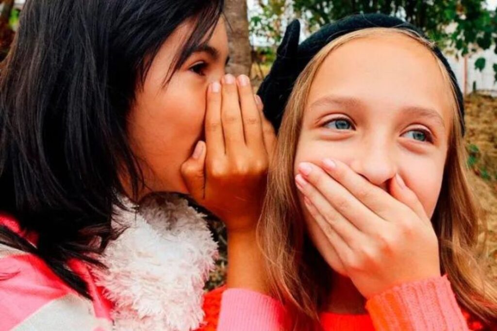 Dos chicas susurrándose al oído sobre noticias falsas en las redes sociales.