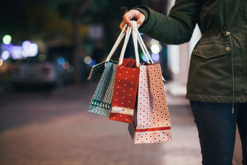 Una mujer sosteniendo bolsas de compras en la calle por la noche en le buen fin.