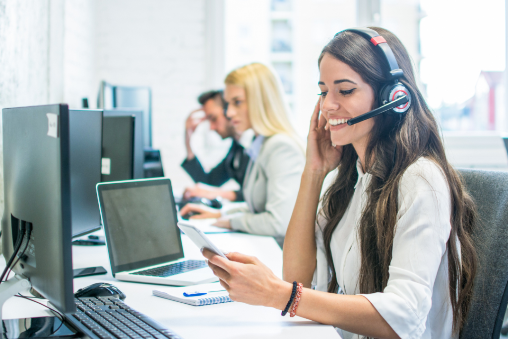 Una mujer que llevaba unos auriculares mientras estaba sentada en un escritorio.