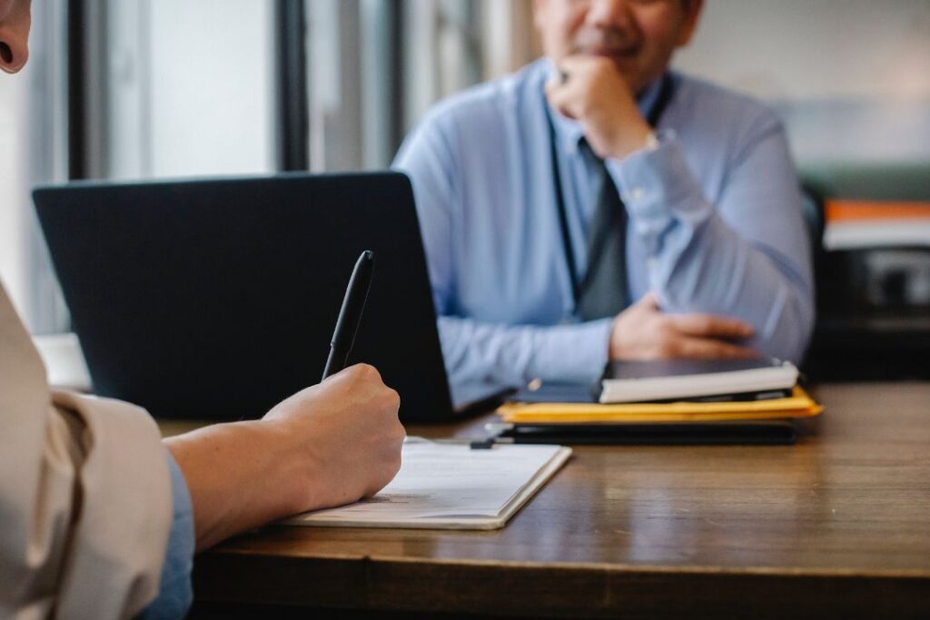 Dos personas sentadas en un escritorio hablando entre sí sobre tareas repetitivas.