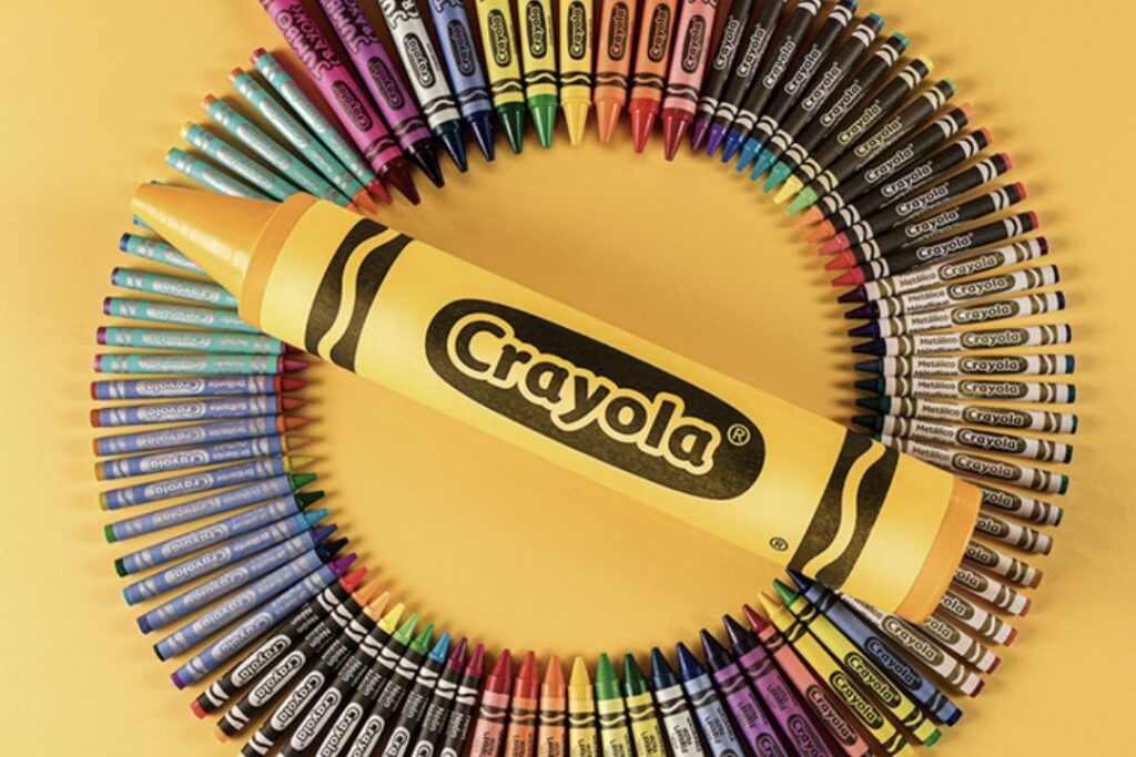 Los crayones Crayola están dispuestos en círculo sobre un fondo amarillo.