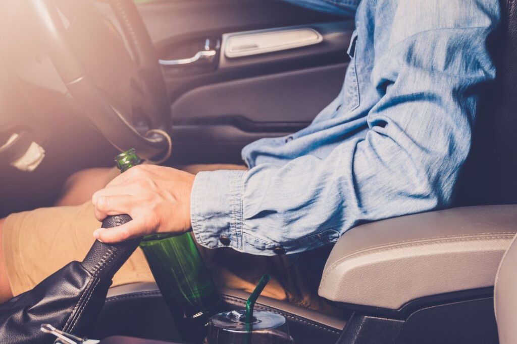 Un hombre en un coche sosteniendo un alcoholímetro.