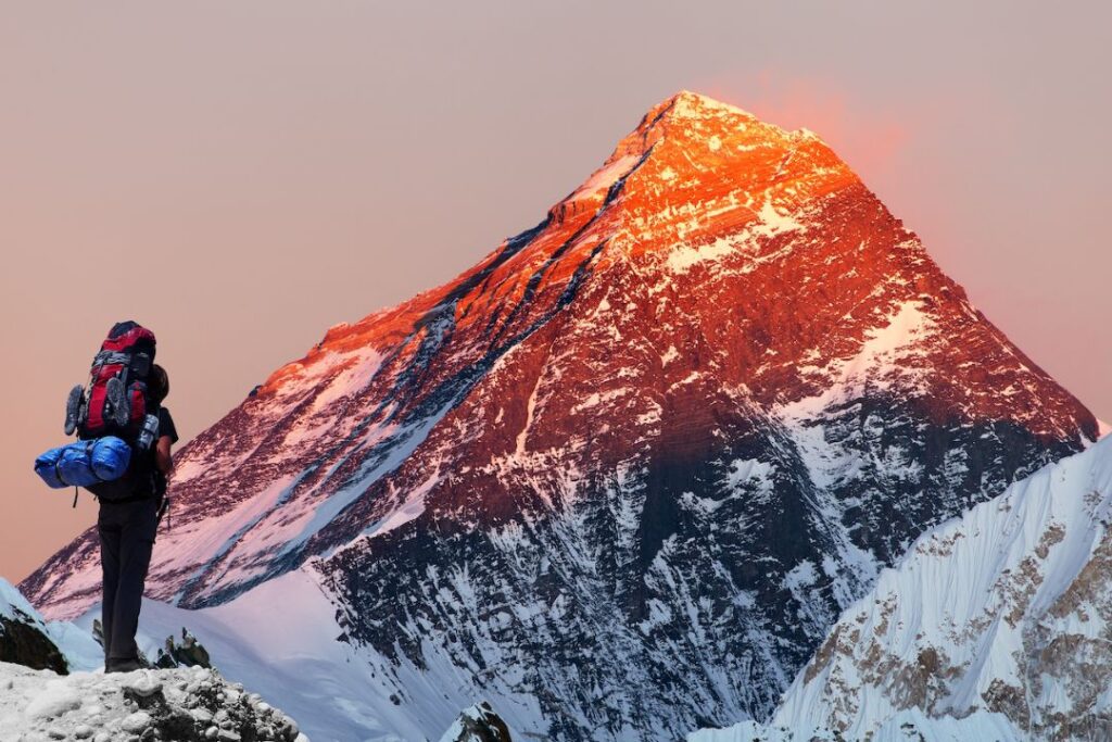 Un hombre está parado en la cima de una montaña con una mochila.