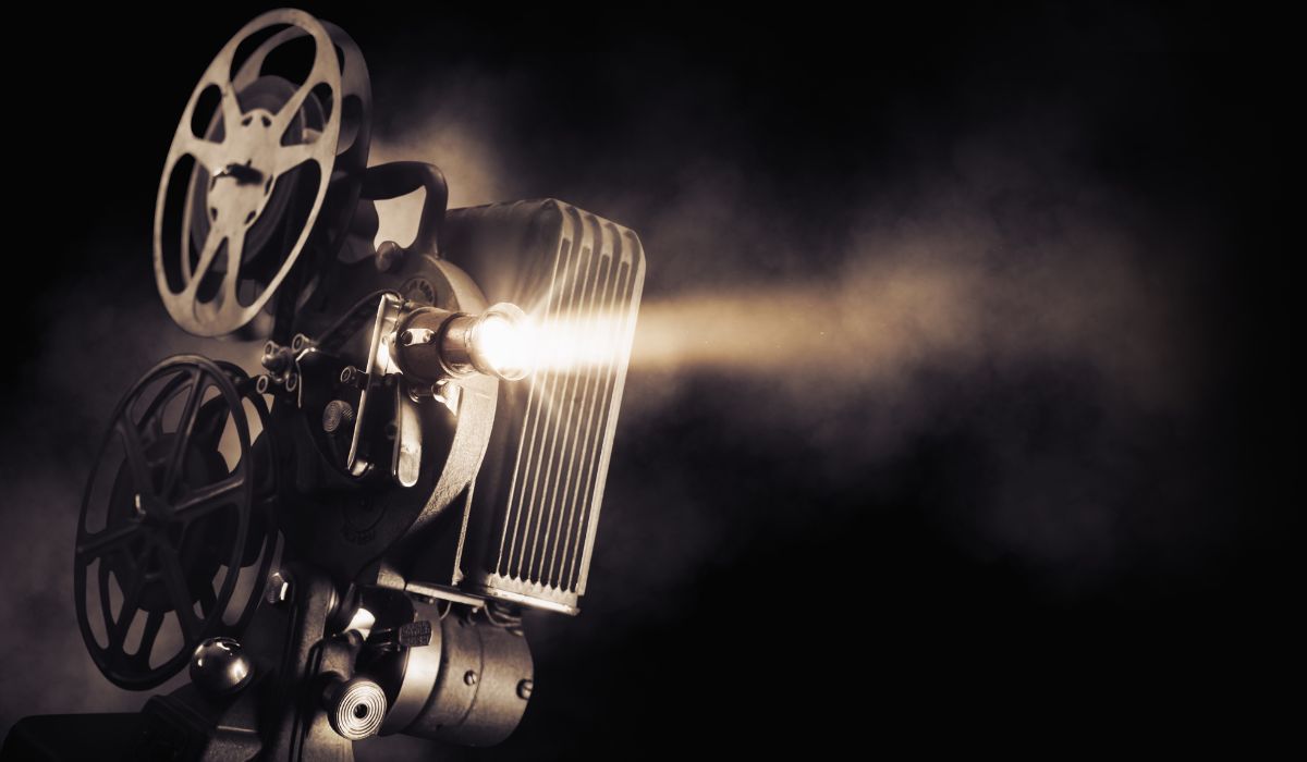 Pobres criaturas se reúnen alrededor de un proyector de cine que proyecta una película sobre un cautivador fondo negro.