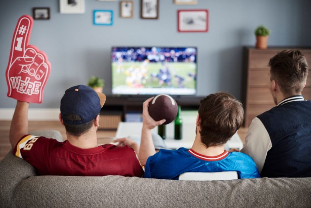 Un grupo de personas se reunieron en un sofá, absortos viendo el Super Bowl.