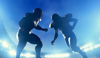 Dos siluetas de jugadores de fútbol corriendo en un estadio durante el Super Bowl.