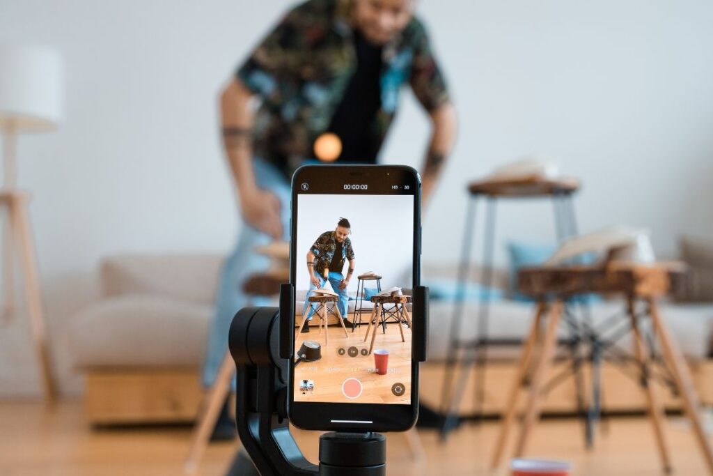 Un hombre captura un momento con un teléfono inteligente en una sala de estar para Tik Tok.