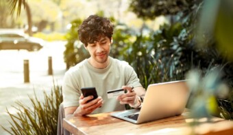 Un consumidor sentado en una mesa con una computadora portátil y una tarjeta de crédito.
