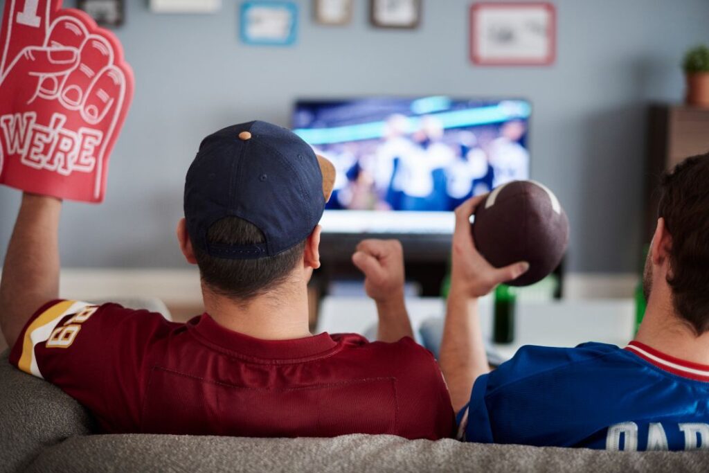 Dos hombres absortos en un partido de fútbol del Super Bowl en la televisión.