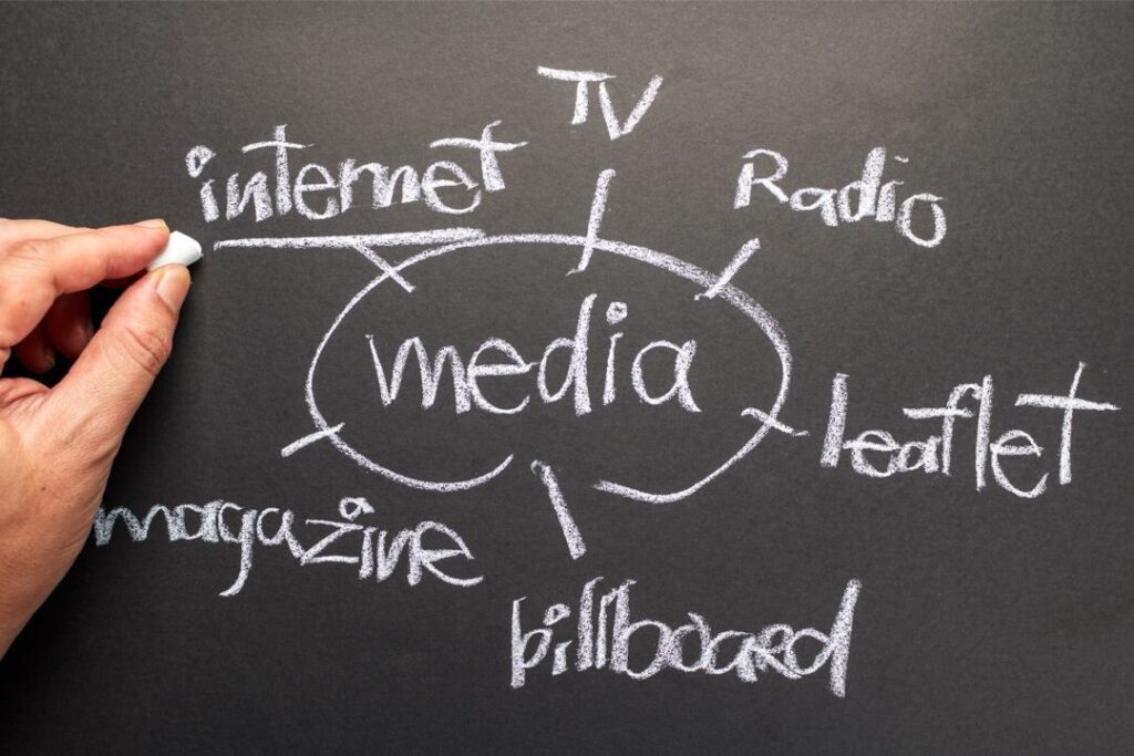 Primer plano de una mano escribiendo en una pizarra un mapa mental relacionado con la "planeación de medios".