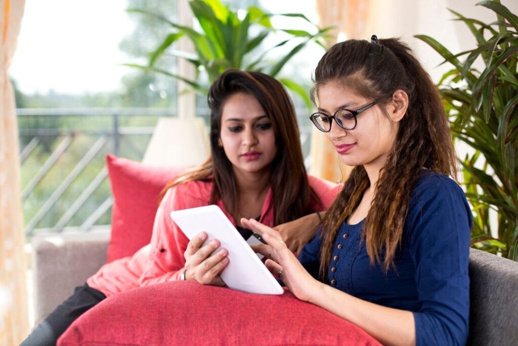 Dos mujeres sentadas en un sofá mirando una tableta.