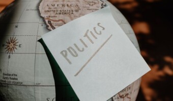 Una nota post-it con las palabras "comunicación política" escrita, colocada sobre un globo terráqueo centrado en el oeste de Estados Unidos.