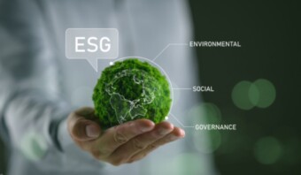 Persona que sostiene un globo terráqueo brillante con etiquetas "modelo ESG", que simboliza la sostenibilidad y la responsabilidad corporativa.