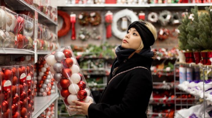 Una mujer sosteniendo un recipiente de plástico lleno de adornos, preparándose para la Navidad.