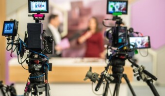 Dos personas son filmadas por múltiples cámaras de video en un estudio, representando a las mejores marcas de la industria.