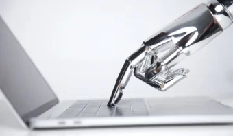 Una mano robótica con dedos metálicos, que simboliza la inteligencia artificial y el marketing, escribiendo con gracia en el teclado de una computadora portátil.
