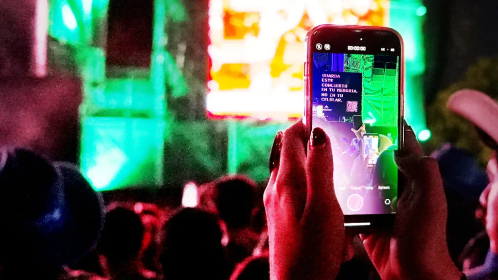 Una persona con The Boring Phone en la mano captura una escena de concierto muy iluminada y repleta de una multitud enérgica.