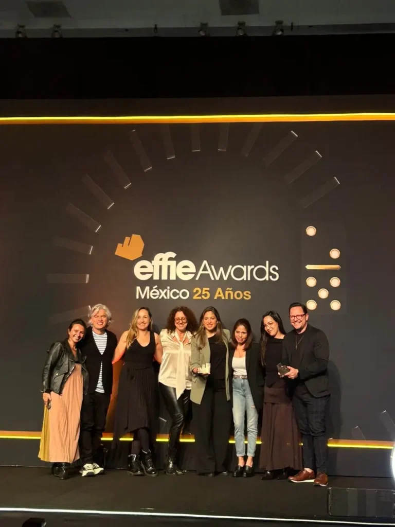 Un grupo de personas de VML México se encuentra en el escenario de los Effie Awards México, celebrando su 25 aniversario, y posando para una foto.