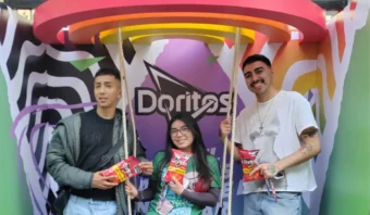 Tres personas se encuentran de pie frente a un fondo vibrante adornado con el logotipo de Doritos, cada una de ellas sosteniendo orgullosamente una bolsa de Doritos. Esta escena brilla intensamente, apoyando a The Trevor Project y celebrando la diversidad con cada crujido.