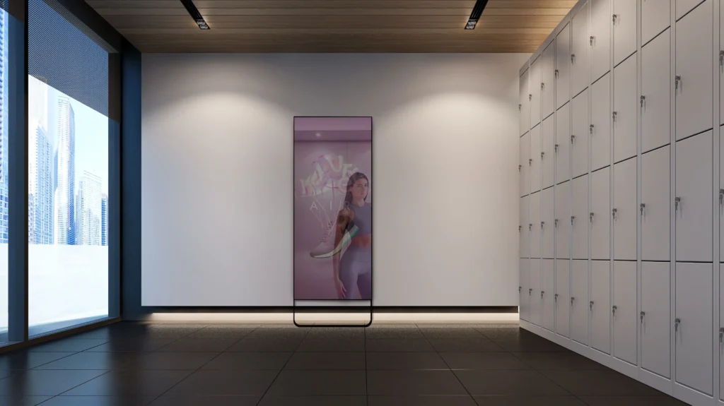 Una mujer se refleja en espejos interactivos en una habitación moderna, donde elegantes armarios se alinean a la derecha y amplias ventanas iluminan la izquierda.