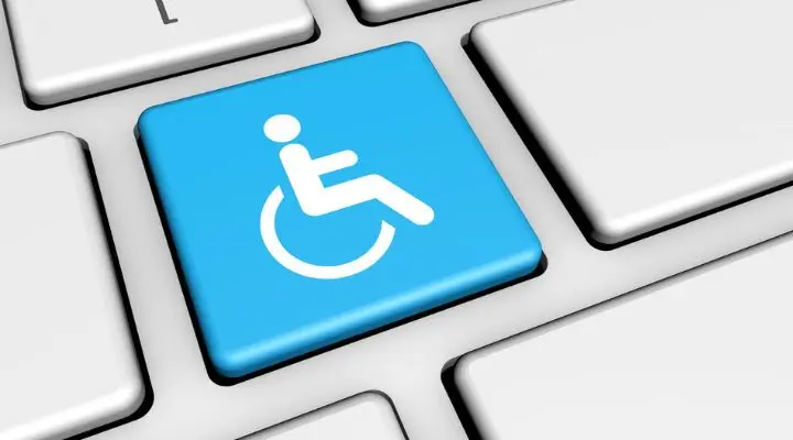 Primer plano de un teclado con una tecla azul que presenta un símbolo blanco de accesibilidad en silla de ruedas, lo que resalta la importancia de la we accesible.