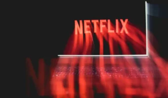 Imagen borrosa de la pantalla de una computadora portátil que muestra el logotipo de Netflix en rojo, con un reflejo distorsionado debajo.