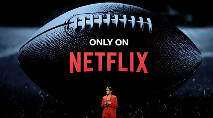 Una persona vestida de rojo se encuentra frente a una imagen grande de una pelota de fútbol americano con una etiqueta que dice "Solo en Netflix" hablando sobre eventos en vivo