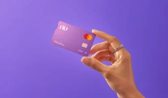 Mano sosteniendo una tarjeta de crédito morada con el logotipo de Mastercard sobre un fondo morado.