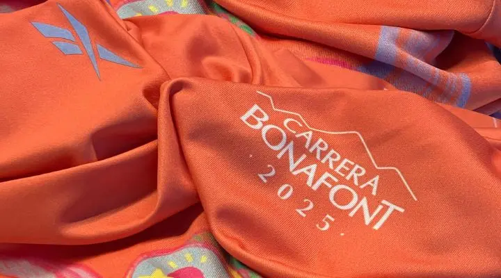 Primer plano de una tela naranja con el texto blanco "Carrera Bonafont 2023" con un pequeño logotipo a la izquierda, que captura el espíritu vibrante que conduce a Carrera Bonafont 2025.