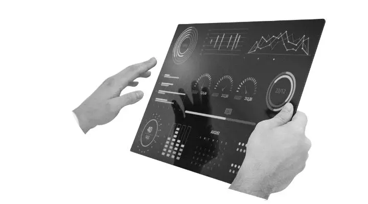 Una persona interactúa con una tableta táctil transparente que muestra varios gráficos y diales digitales, lo que resalta la importancia de la data readiness en la tecnología moderna.