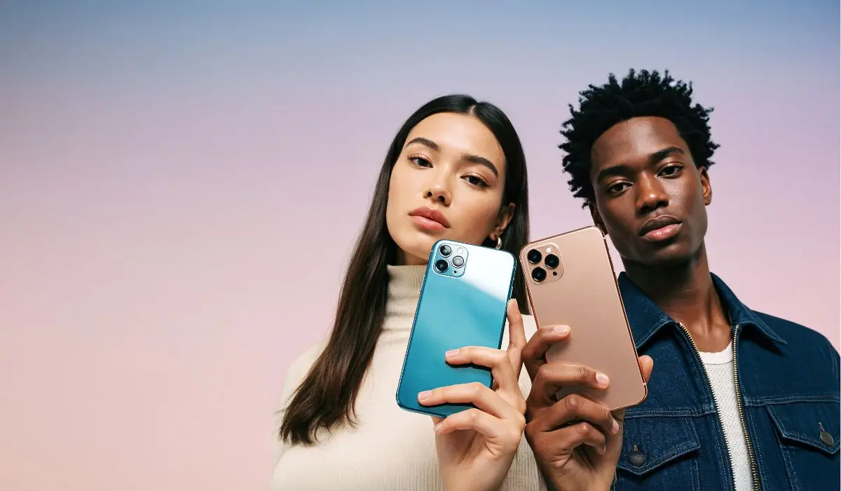 Dos personas sostienen un smartphone cada una, uno en azul y otro en dorado, sobre un fondo pastel degradado.