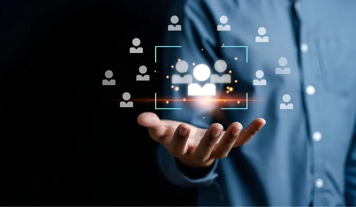 Una persona extiende su mano con íconos digitales de personas y un cuadrado brillante, que simboliza el lado humano del CRM y el proceso de selección o selección de individuos, sobre un fondo oscuro.