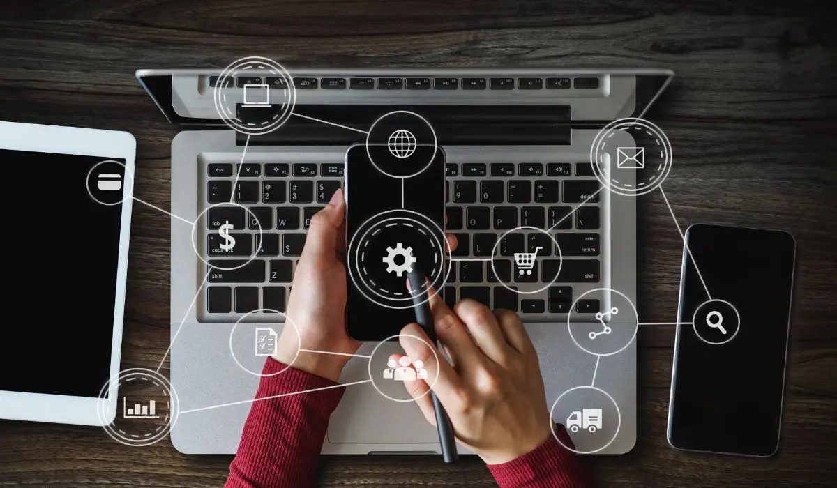 Una persona usa un teléfono inteligente frente a una computadora portátil, con íconos digitales superpuestos, que simbolizan servicios en línea y funciones tecnológicas, perfectos para explorar las netas del marketing digital.