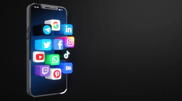 Un teléfono inteligente muestra íconos 3D de aplicaciones de redes sociales populares como Facebook, Twitter, Instagram, LinkedIn y más, flotando frente a la pantalla sobre un fondo oscuro: una imagen inspiradora para cualquiera que busque crear una app.
