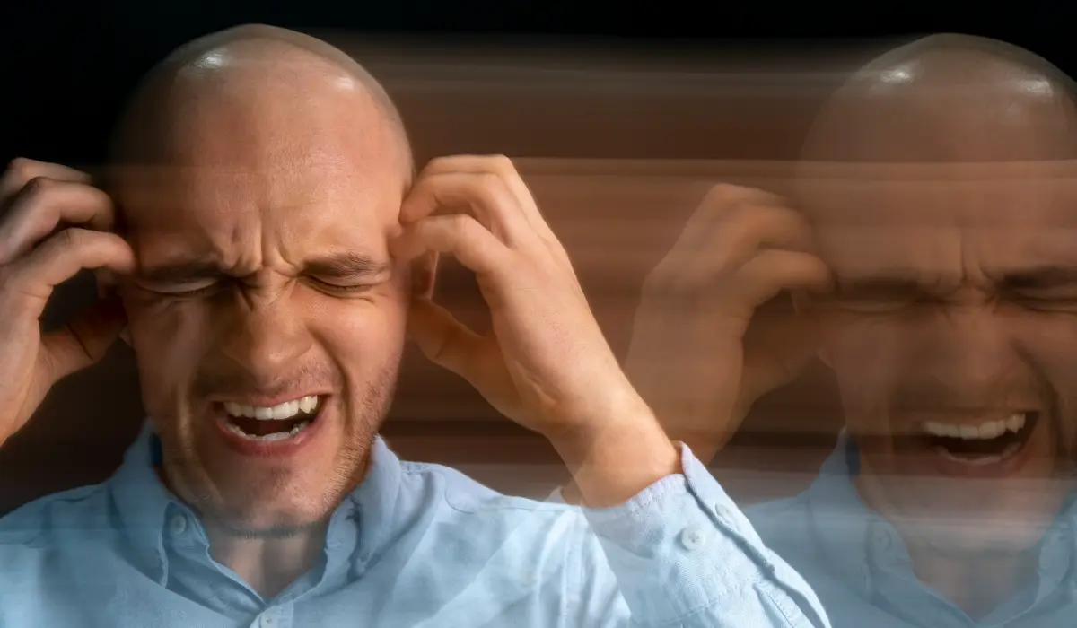 Un hombre con la cabeza rapada cierra los ojos con fuerza y se toca las sienes en aparente angustia, con un efecto de imagen duplicada borrosa que sugiere confusión, dolor o la agitación que a menudo se ve en medio de la ira social en México. ¿Es la reacción adecuada?.